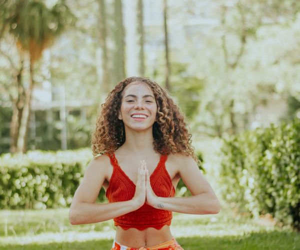 Smiling woman stretching gently on a yoga mat outdoors.